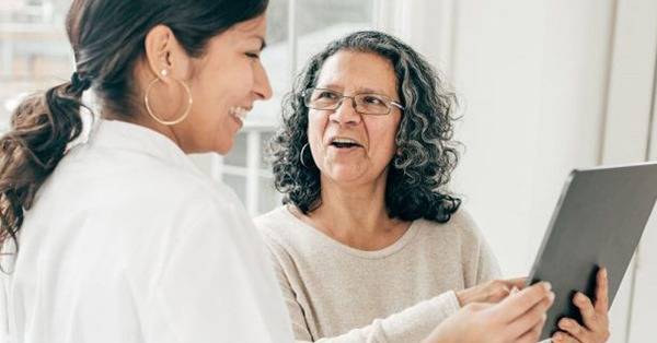 patient and caregiver smiling, reviewing data on a tablet
