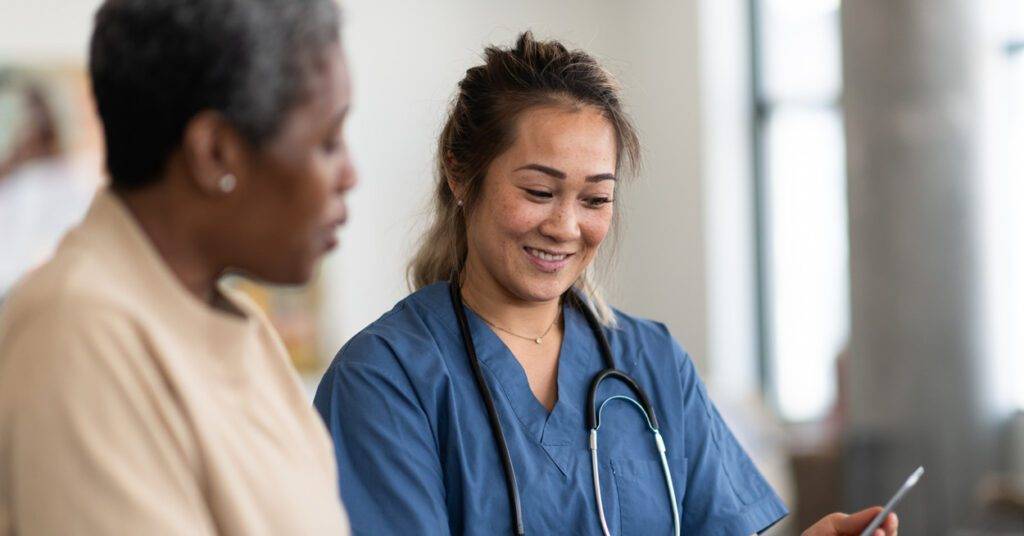 healthcare professional shows phone to elderly patient