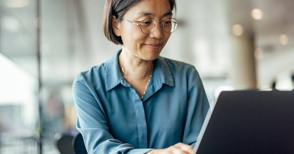 Asian woman works on laptop